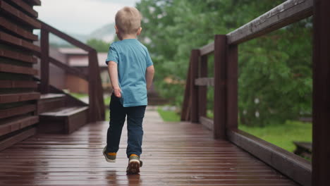 playful toddler boy runs along veranda deck at cottage house