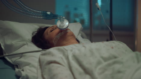 Patient-with-oxygen-mask-lying-hospital-bed-in-hospital-intensive-care-unit.