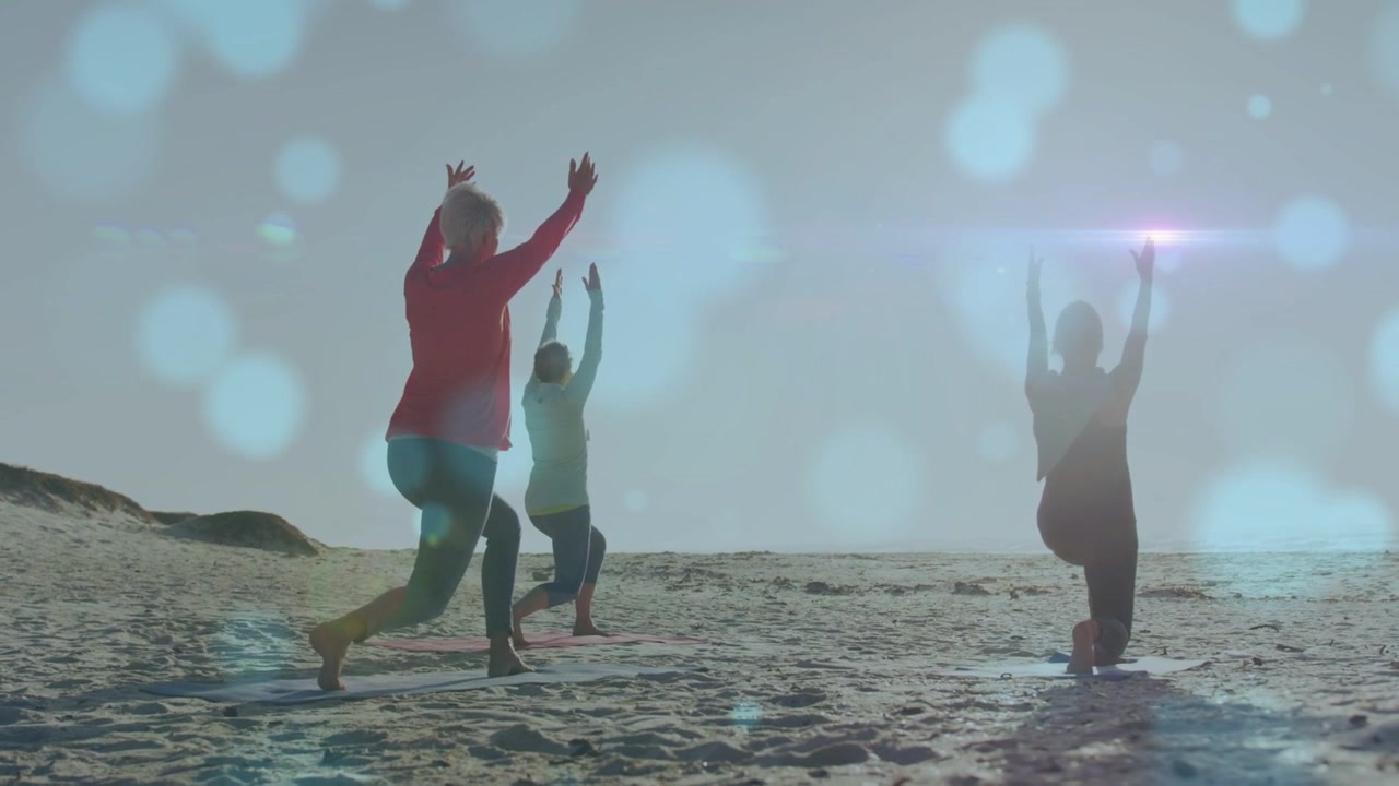 Left woman stepping forward leading trio moving to syncing yoga poses by sea bokeh sweeping shadows