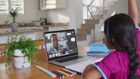 Schoolgirl-using-laptop-for-online-lesson-at-home,-with-her-school-friend-and-web-chat-on-screen