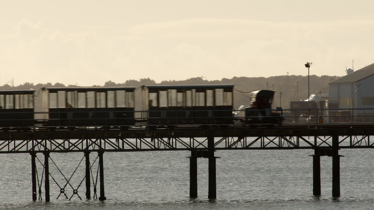 Hythe Pier Railway train in silhouette going left to right of frame