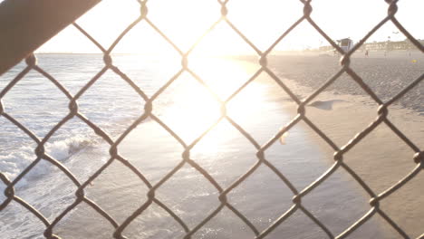 sunset california ocean through chainlink