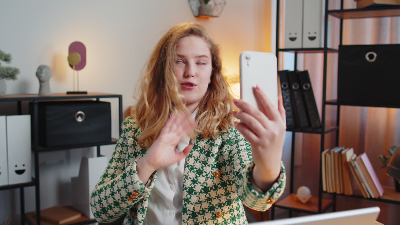 Donna d'ufficio che saluta con un gesto di saluto accoglie qualcuno su uno smartphone webinar online