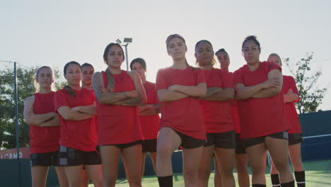 portrait of determined female soccer team on training ground against flaring sun