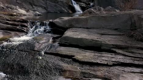 Slow-sideways-drone-flight-over-water-in-near-of-a-waterfall-at-daytime