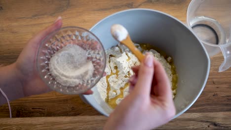 woman adding salt to flour and eggs in a bowl