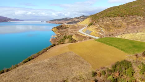 colorful slopes of mountains around beautiful lake with panoramic road alongside coastline on a bright sunny winter day