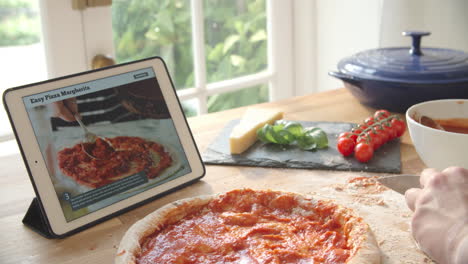 persona que sigue la receta de la pizza usando una aplicación en una tableta digital