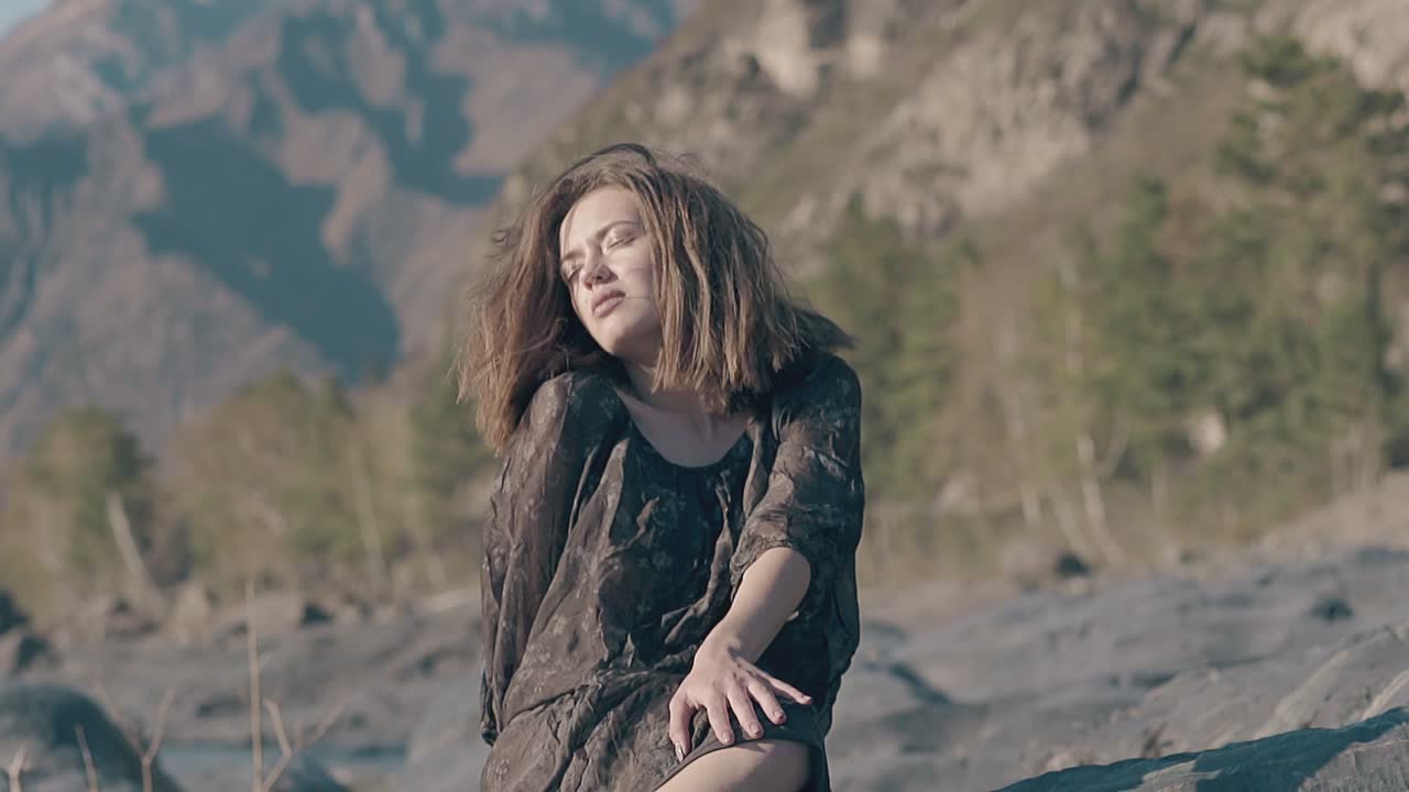 chica de cabello rojo ondeando en el viento en una gran piedra en cámara lenta