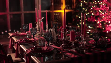 dining table prepared for christmas dinner. festive table decorated with candles on christmas tree background with lights. festive serving.