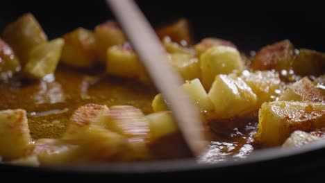 person stirring in pan with dices of potatoes, cooking delicious vegetarian food