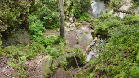 a man helps a woman to climb a steep path trekking in the forest hiking and active lifestyle