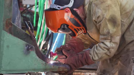 arc welder in full protective suit and mask welding steel structure in a factory using non-consumable tungsten electrode - close up slowmo