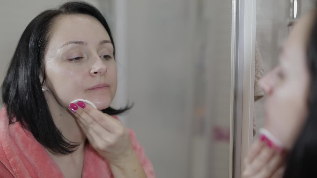 Beautiful brunette woman using cotton pads. Woman removing makeup