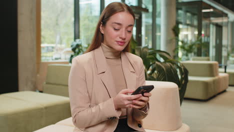 caucasian business woman using smartphone texting share messages content working in office lobby