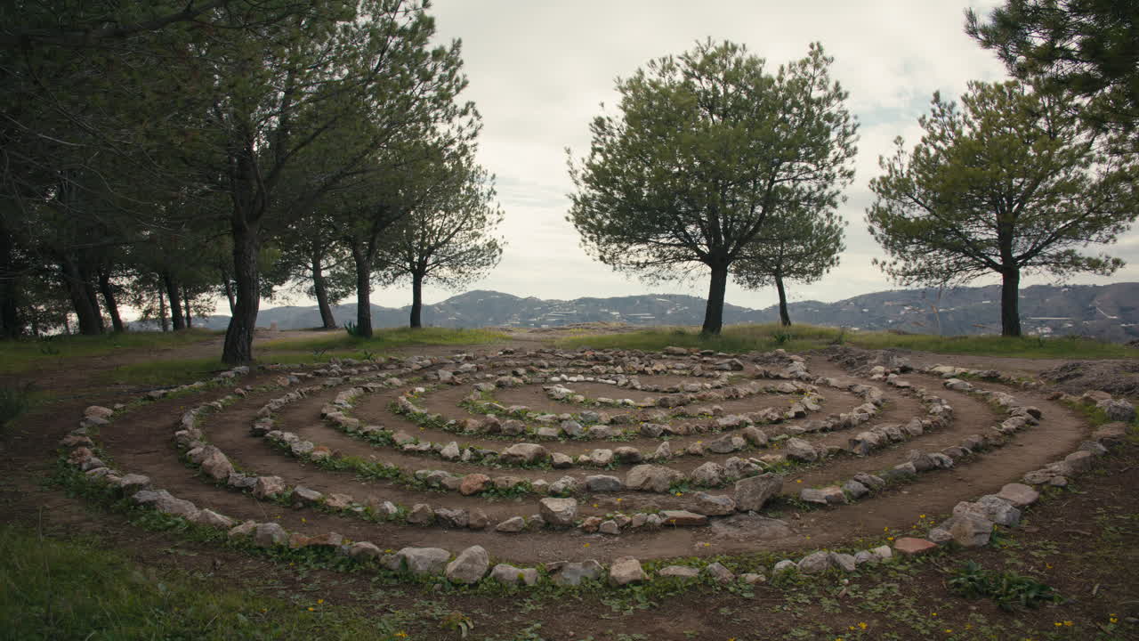 Labirinto a spirale fatto a mano con pietre, immerso in una radura tranquilla nella foresta con montagne distanti sullo sfondo