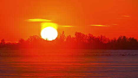 lapso de tiempo del sol cegador saliendo en un cielo dorado sobre un paisaje nevado