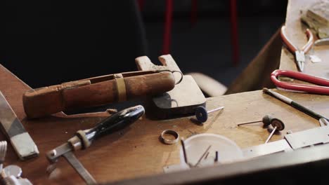 primer plano de herramientas de artesanía y anillos en la mesa en el estudio en cámara lenta