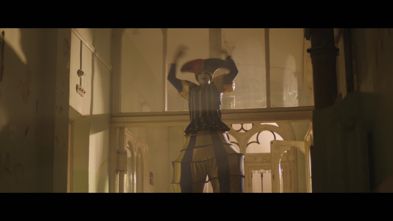 A girl and strange clown on stilts in a dark corridor at night