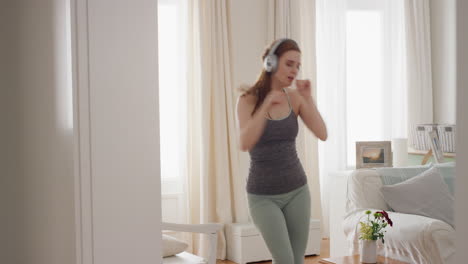 mujer divertida bailando en casa con auriculares escuchando música celebrando con movimientos de baile funky disfrutando de la libertad divirtiéndose el fin de semana 4k