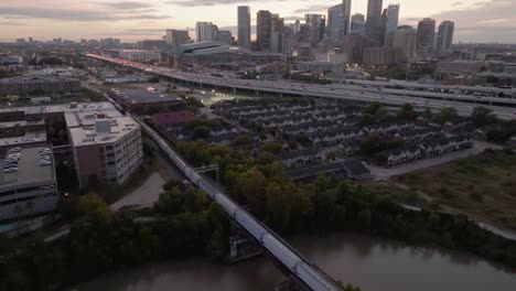 train in front of i-69 and the houston skyline, dusk in texas, usa - aerial view