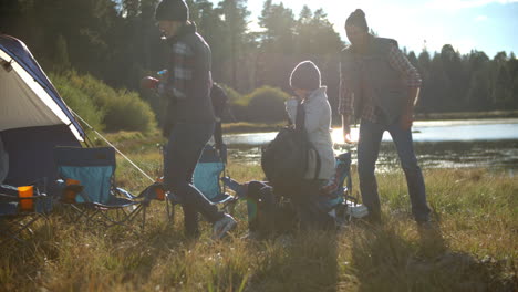 Family-arriving-back-to-lakeside-tent-after-fishing