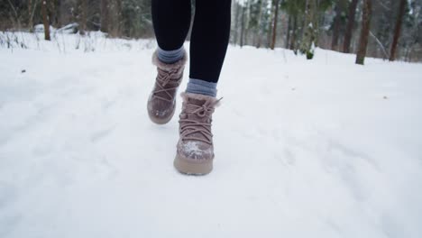 woman walking through snowy forest path