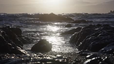 ocean tide coming by in slow motion between the rocks at the beach