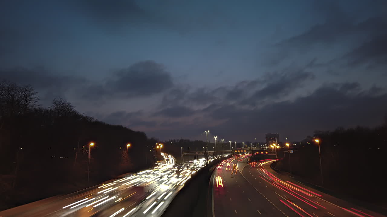 Motionlapse capturing the heavy traffic of Antwerp’s Ring Road at night in Belgium, with dynamic light trails from vehicles and moving clouds clearing up in the sky