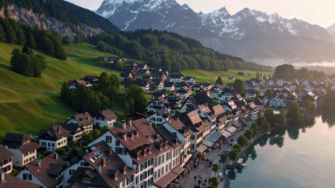 Aerial video of a picturesque village by a serene lake, surrounded by lush hills and majestic