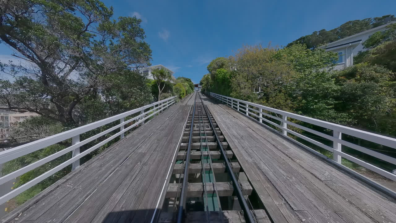 Wellington Cable Car track ascending through lush hillside homes and gardens. A beloved part of the city’s character, the cable car offers a scenic ride from Lambton Quay to the Botanic Gardens