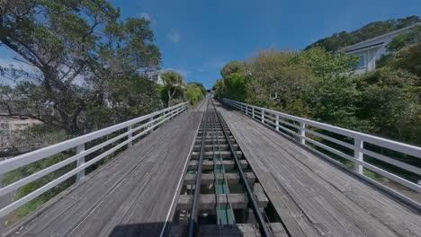 wellington cable car track ascending through lush hillside homes and gardens. a beloved part of the city’s character, the cable car offers a scenic ride from lambton quay to the botanic gardens