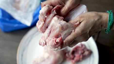 primer plano de las manos cortando pollo crudo con un cortador tradicional aruvamanai