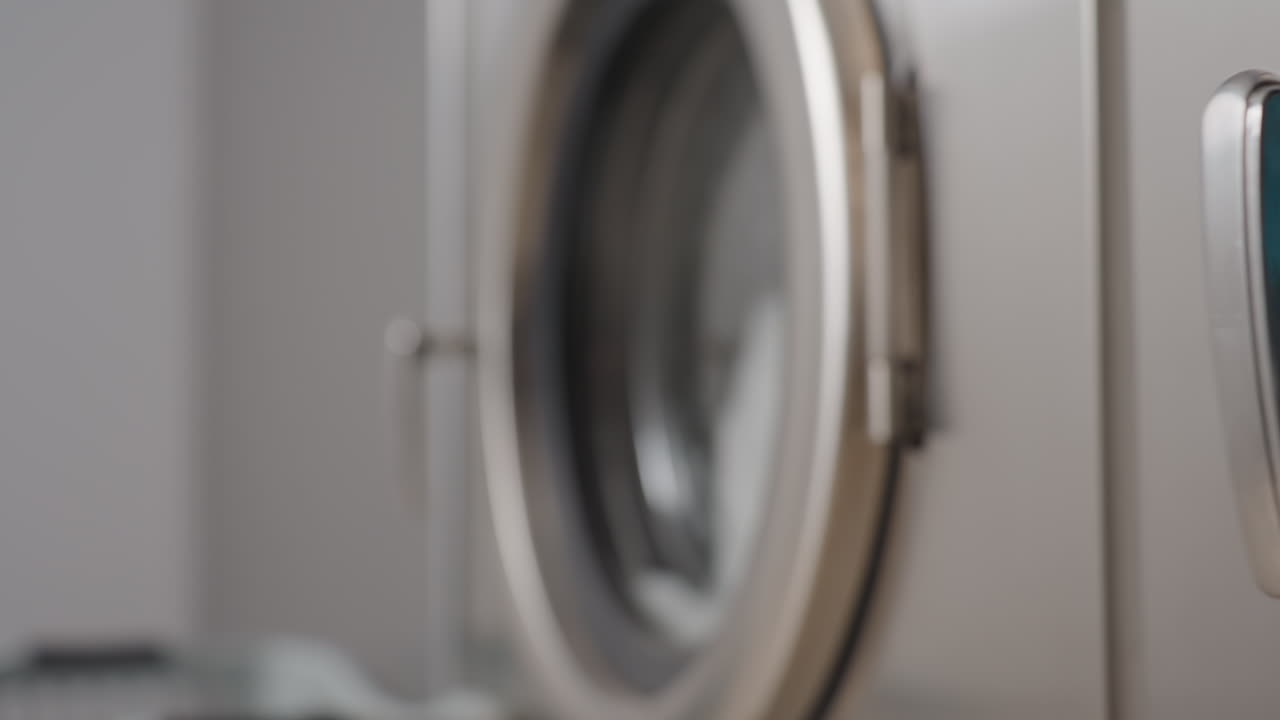 Close up components of washing machine row showing doors and handles, inner view revealing clothes soaking in bubbling water, detailed focus on stainless finish and laundry process inside laundromat