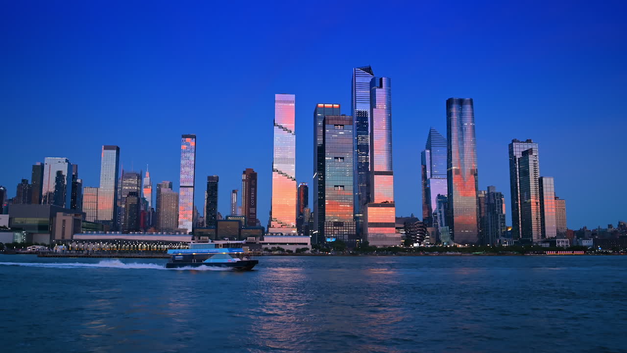 New York, USA, 28 August 2025: Modern motor boat carrying people moves quickly by the blue waterscape of the East River. Stunning skyscrapers and high-rises of Manhattan reflect the soft light of setting sun. View from the riverscape