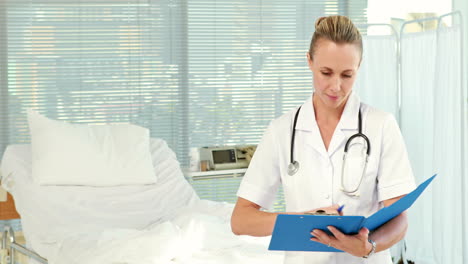 doctor writing on clipboard and looking at camera