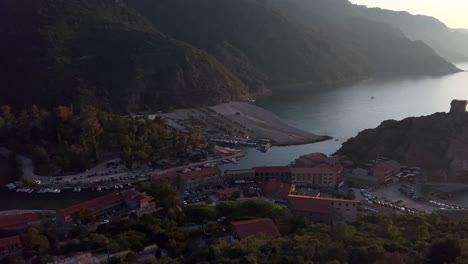 Aerial-panoramic-panning-view-of-Porto-Ota-town-at-sunset-in-Corsica,-France