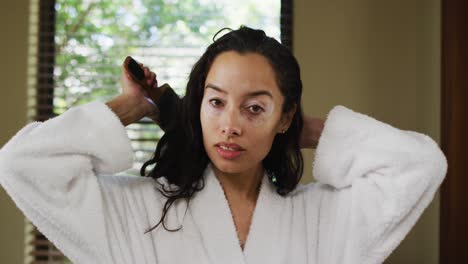 Portrait-of-biracial-woman-in-robe-brushing-hair