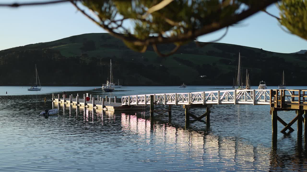 A tranquil lakeside scene with a pier, boats, and gentle sunset lighting, creating a peaceful and reflective atmosphere