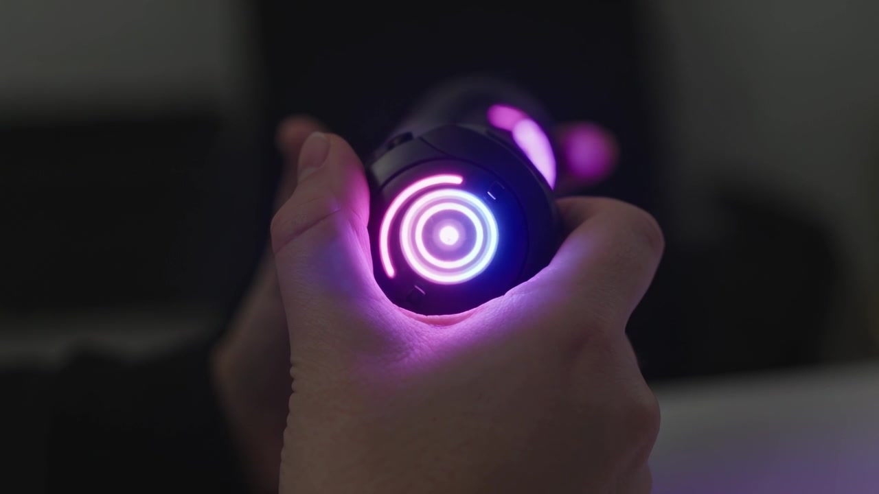 Powering on, adult hands rotating and tightening grip at dimly lit desk, testing concentric LEDs