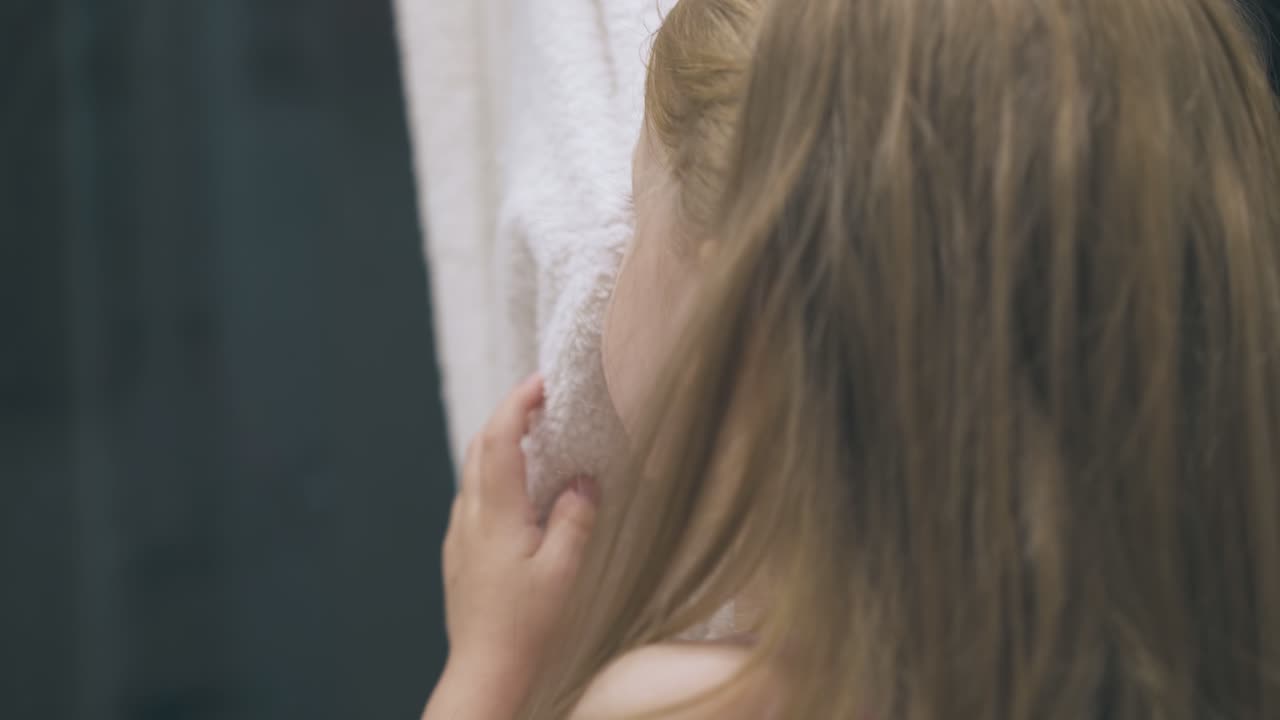 작은 소녀는 가 ⁇ 운 욕실에서 부드러운 수건으로 얼굴을  ⁇ 습니다.