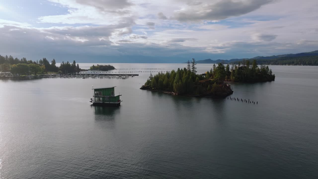 Isole boscose che emergono dalle calme acque blu del lago, circondate da case galleggianti e pontili della marina, Lago Flathead, Montana, USA.