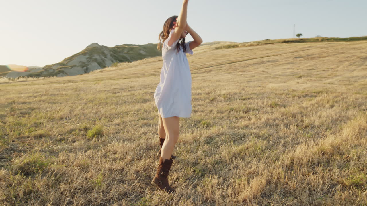 mujer bailando en un campo al atardecer