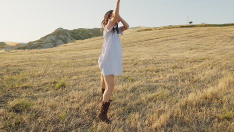 woman dancing in a field at sunset