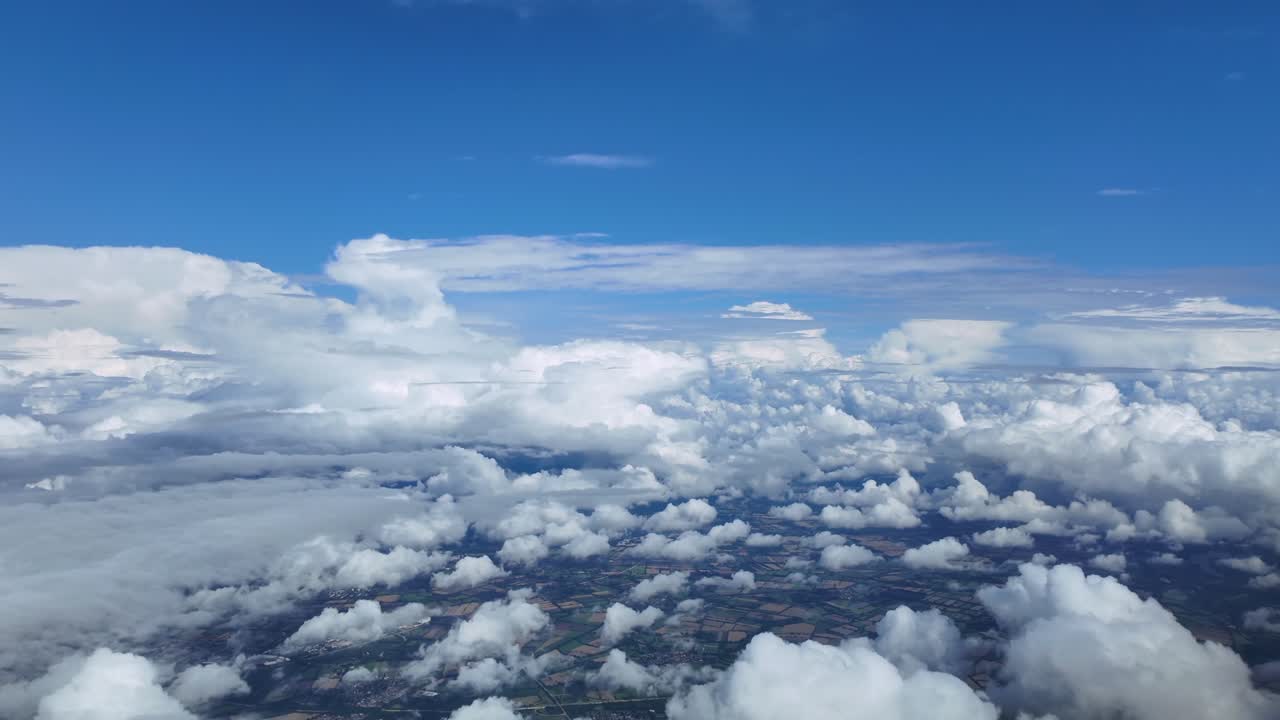 A peaceful cloudscape through the pilot’s eyes of a jet airplane floating through white cottony storm clouds under a deep blue sky
