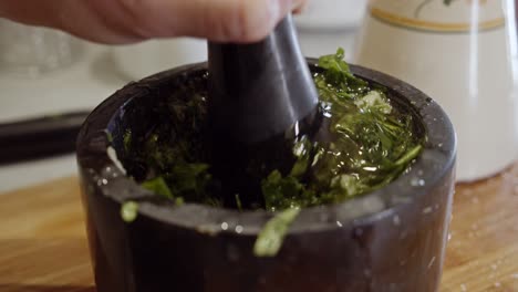 machacar a mano una salsa saludable con hierbas en un tazón negro de cerámica