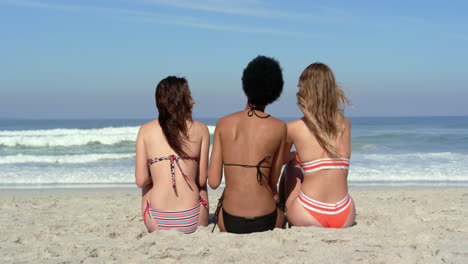 young female friends sitting together at beach 4k