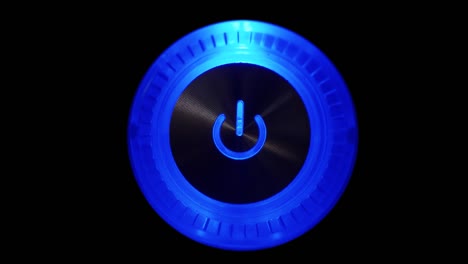 4k macro video loop of a lightning-up computer power button on the system unit on a black background.