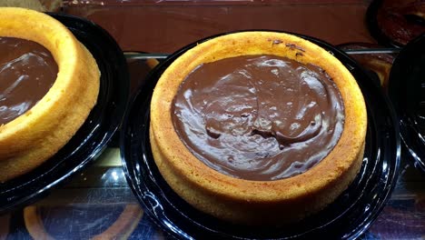 corn cake with chocolate cream frosting, being displayed in a showcase of a brazilian bakery.