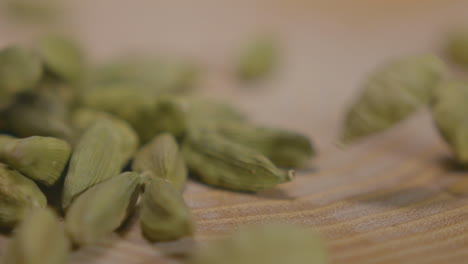 Cardamom-pods-falling-into-frame-on-wooden-platform